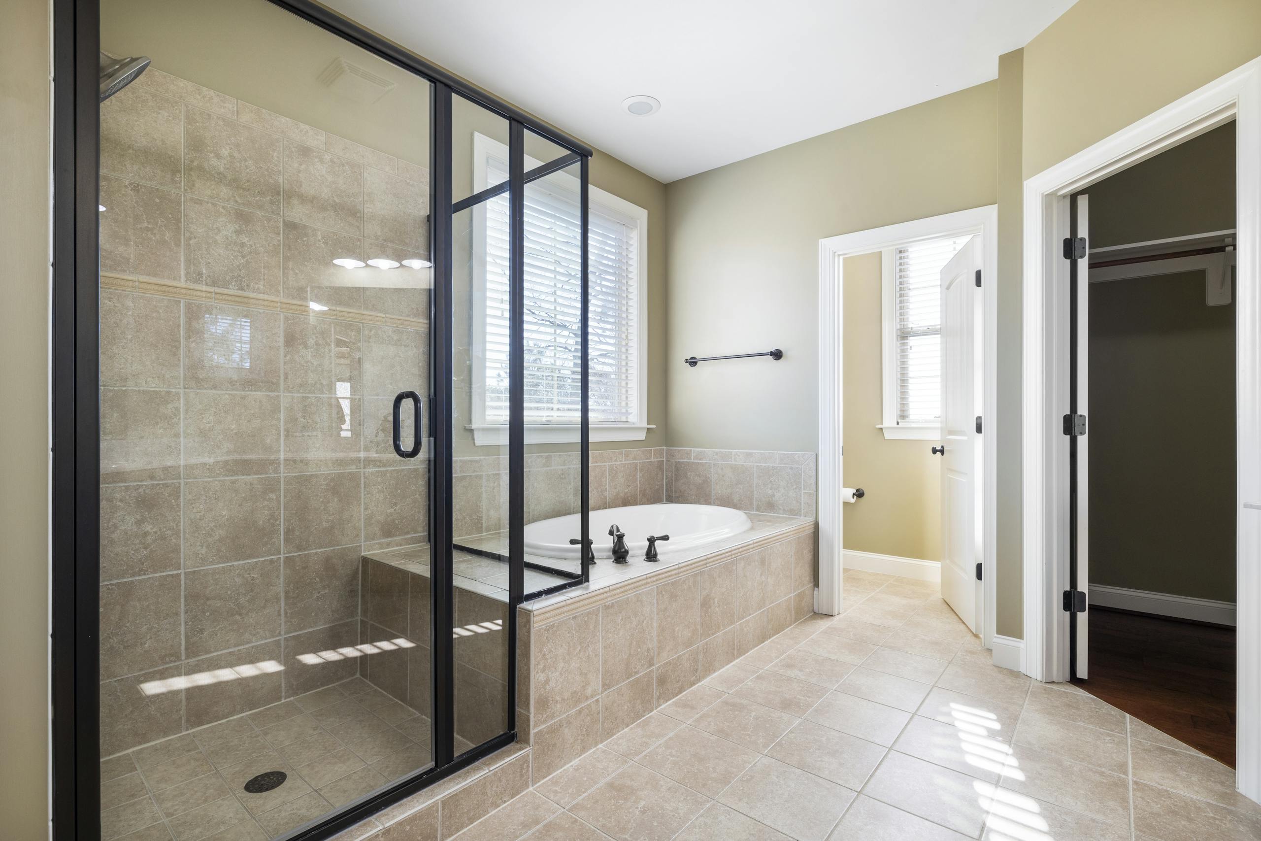 Spacious and bright bathroom featuring glass shower and built-in bathtub with natural light.